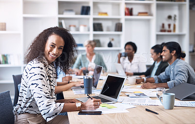 Buy stock photo Portrait of a young businesswoman working on a laptop in an office with her colleagues in the background