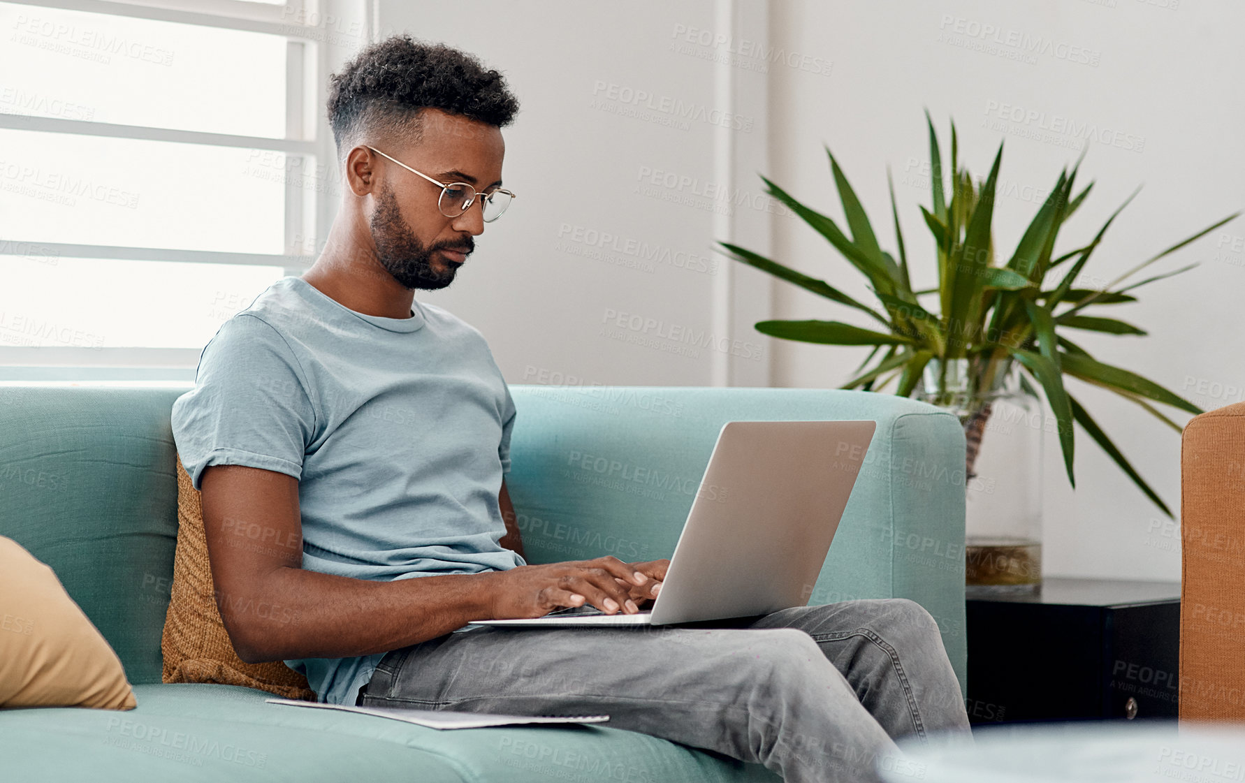 Buy stock photo Laptop, remote work and black man typing in home for research, project or online report. Freelancer, computer and copywriter on sofa writing article, story or reading email on internet in living room