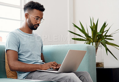 Buy stock photo Laptop, freelancer and black man typing in home for research, project or online report. Remote work, computer and editor on sofa for writing article, story or reading email on internet in living room