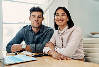 Buy stock photo Cropped portrait of two young businesspeople sitting together in the office during the day