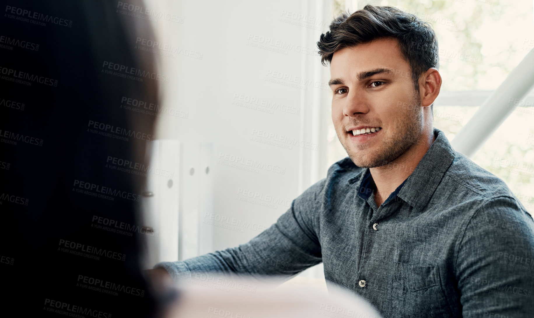 Buy stock photo Cropped shot of a handsome young businessman sitting with a colleague in the office during the day