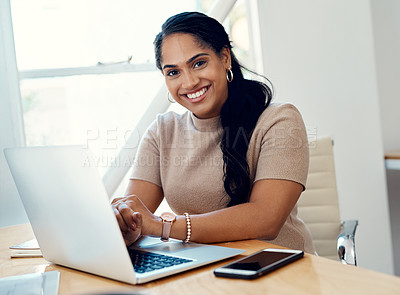 Buy stock photo Cropped portrait of an attractive young businesswoman sitting alone and using her laptop in the office