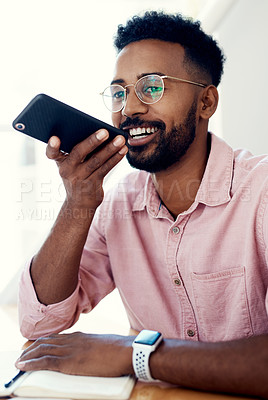 Buy stock photo Cropped shot of a handsome young businessman sitting alone in the office and sending a voice note on his cellphone
