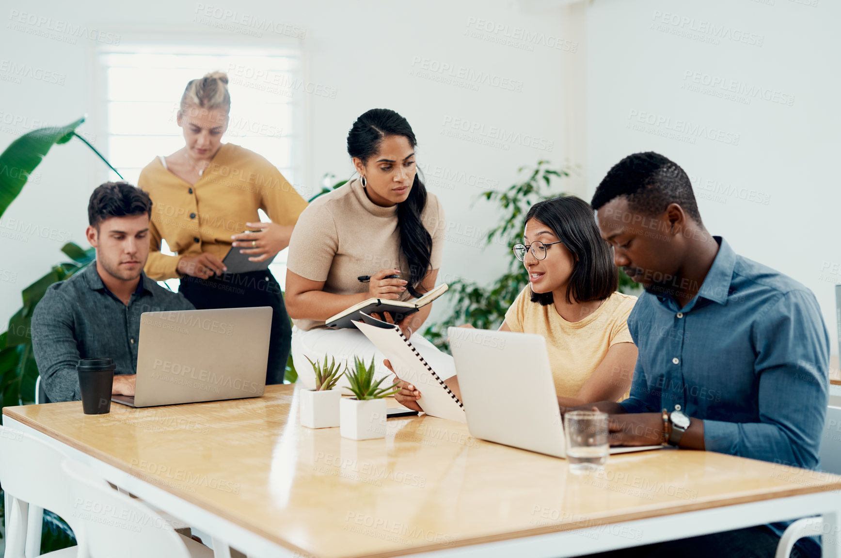 Buy stock photo Cropped shot of a diverse group of businesspeople sitting together in the office to strategise