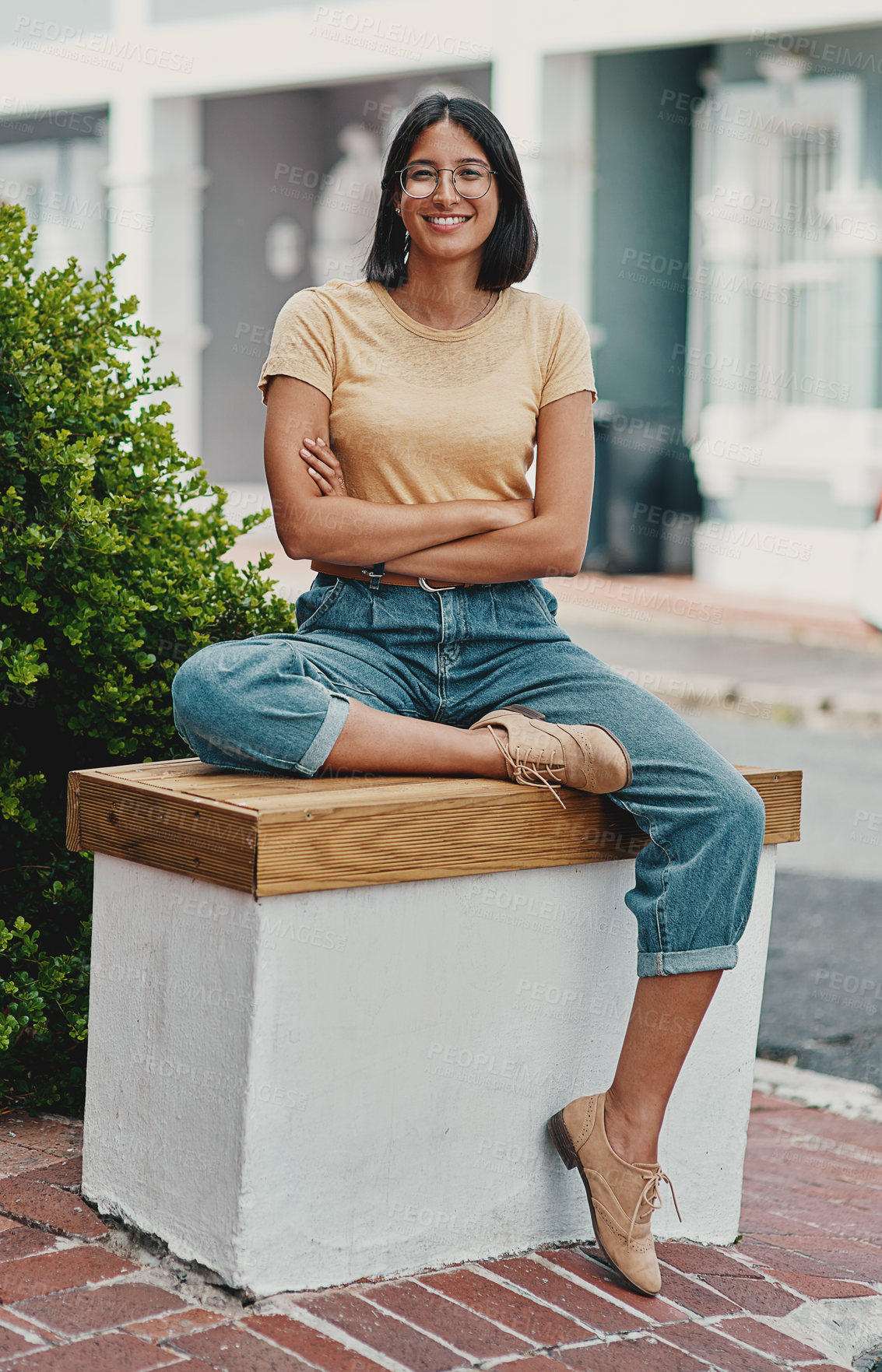 Buy stock photo Full length portrait of an attractive young businesswoman sitting alone outside with her arms crossed during the day