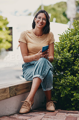 Buy stock photo Full length portrait of an attractive young businesswoman sitting outside alone and using her cellphone