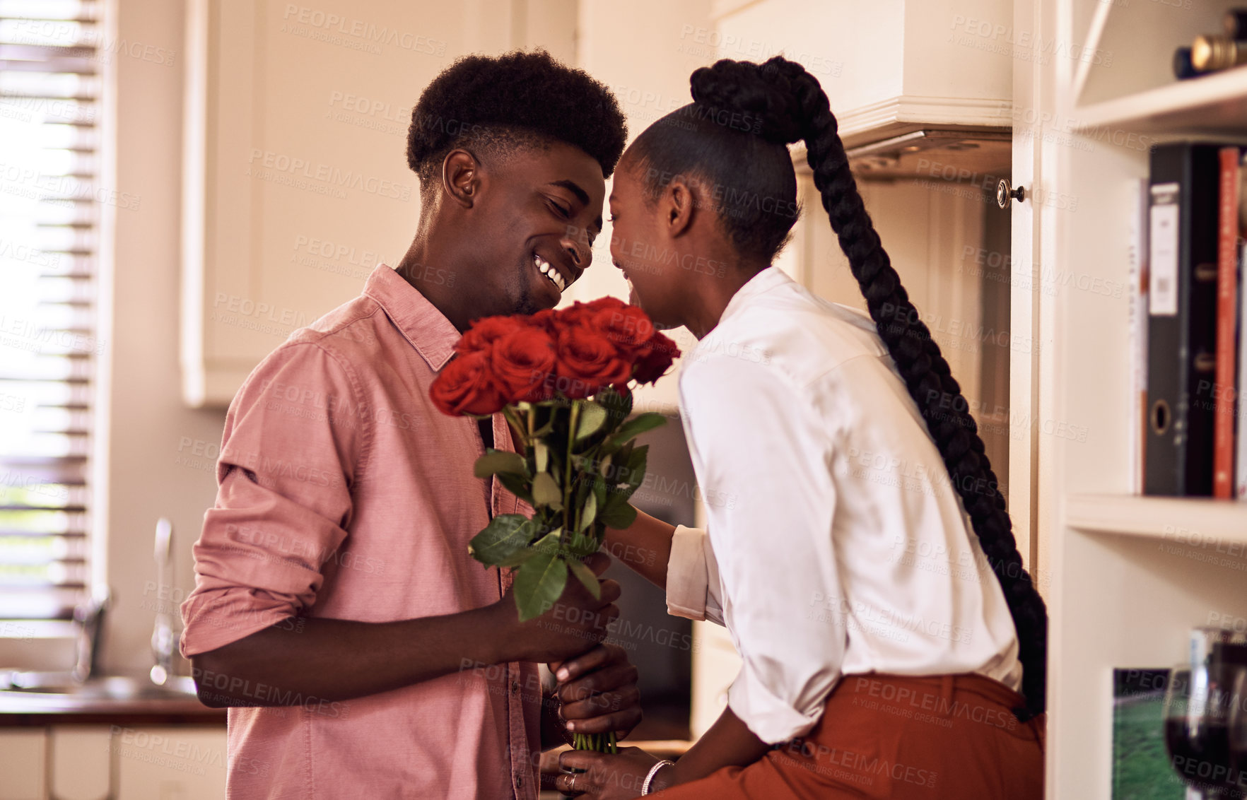 Buy stock photo Cropped shot of an affectionate young man giving his wife a bunch of roses in their kitchen at home