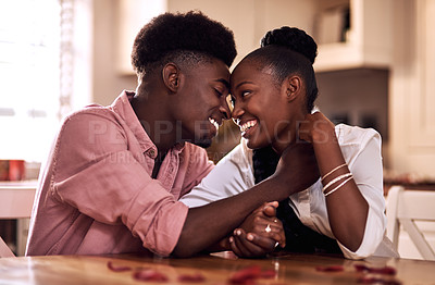 Buy stock photo Cropped shot of an affectionate young couple smiling at each other while sitting in their kitchen on Valentine's day