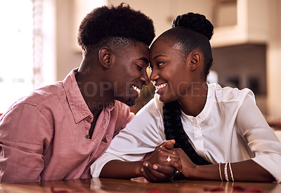 Buy stock photo Cropped shot of an affectionate young couple smiling at each other while sitting in their kitchen on Valentine's day