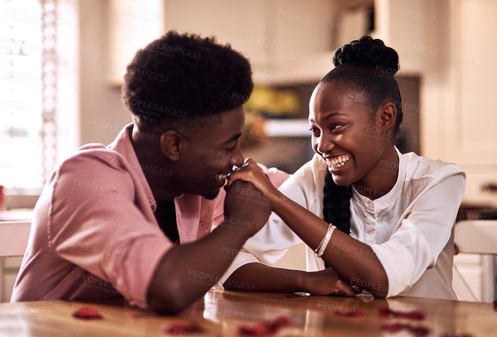 Buy stock photo Black couple, kitchen and smile in home with love, romance and bonding together with rose petals. Happy, man and woman holding hands with trust, relax and celebrating Valentines day or anniversary