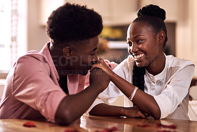 Buy stock photo Cropped shot of an affectionate young man kissing his wife's hand while sitting in their kitchen at home
