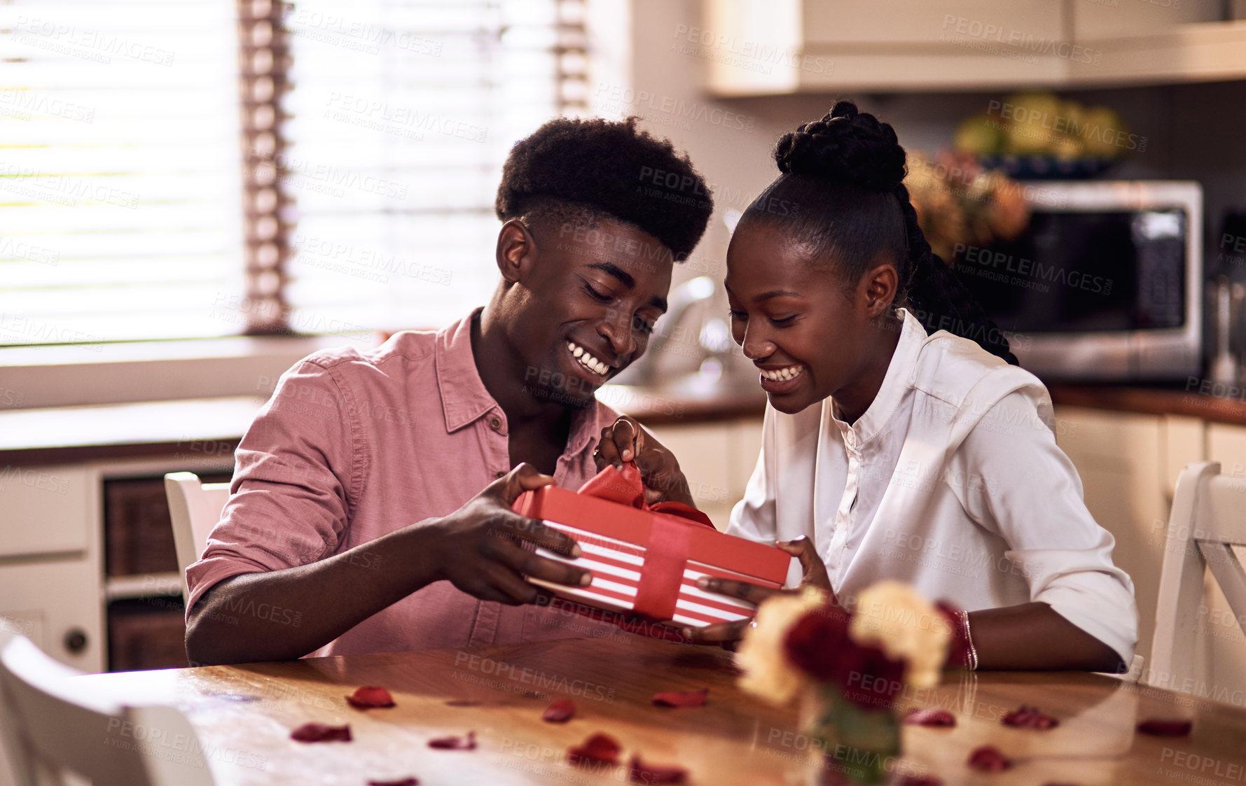 Buy stock photo Cropped shot of an affectionate young man giving his wife a wrapped gift on Valentine's day at home