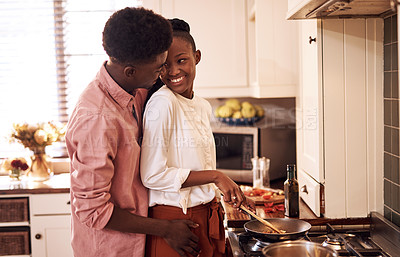 Buy stock photo Cropped shot of an affectionate young man hugging his wife while she's cooking in their kitchen at home