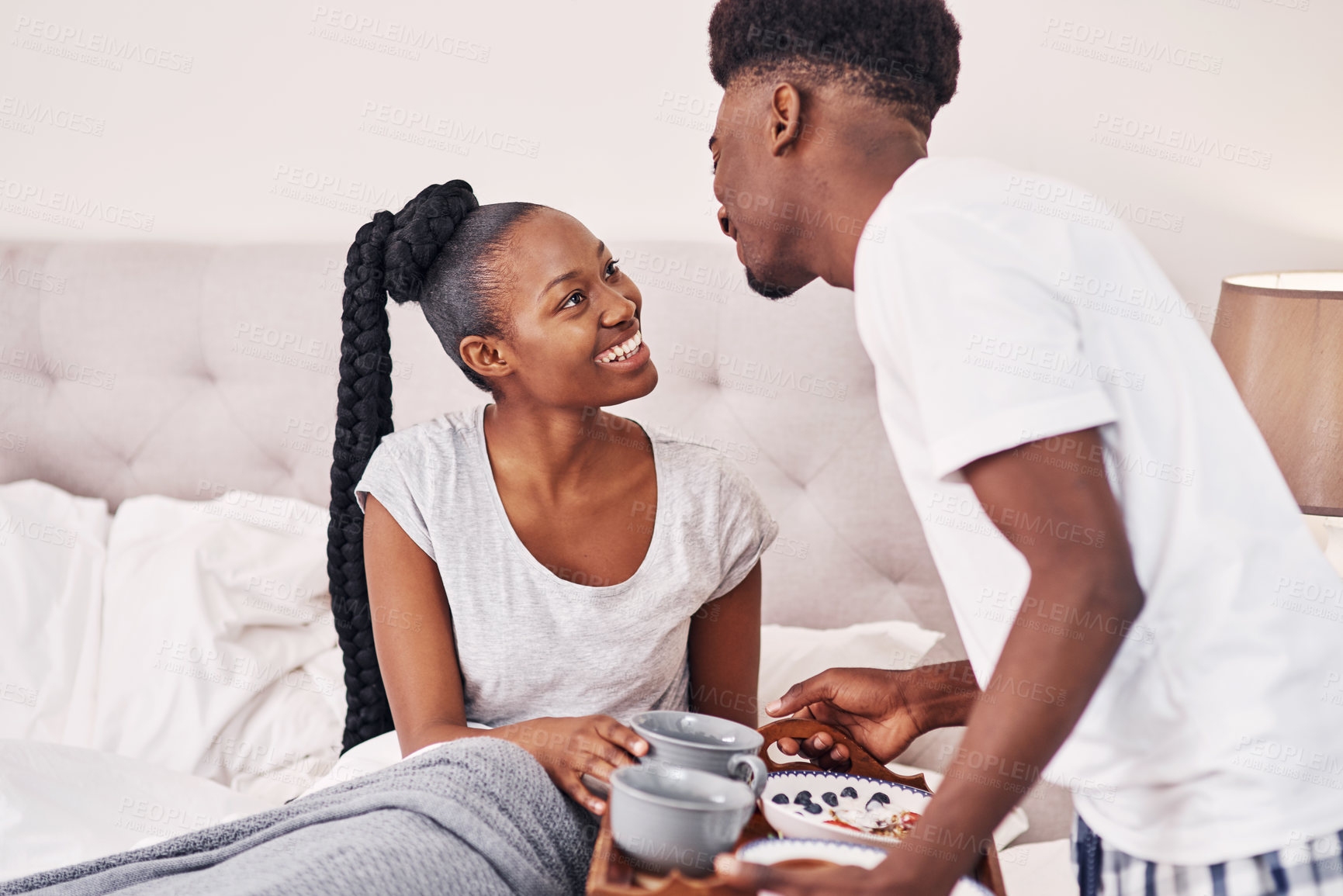 Buy stock photo Shot of a young man bringing his girlfriend breakfast in bed