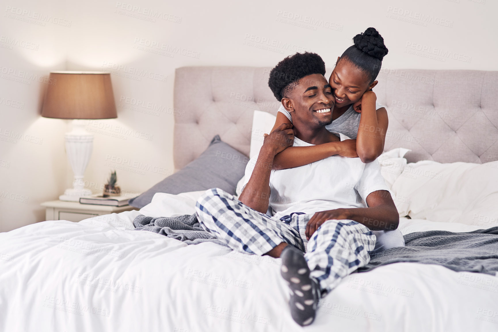 Buy stock photo Shot of an affectionate couple relaxing on their bed wearing pajamas