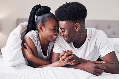 Buy stock photo Shot of an affectionate couple relaxing on their bed wearing pajamas