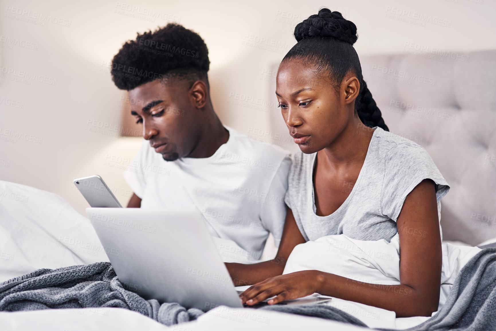 Buy stock photo Black couple, laptop and bedroom with mobile phone, wake up in communication in home. African people, together and tech for streaming, online activity and connection for movies or social network app