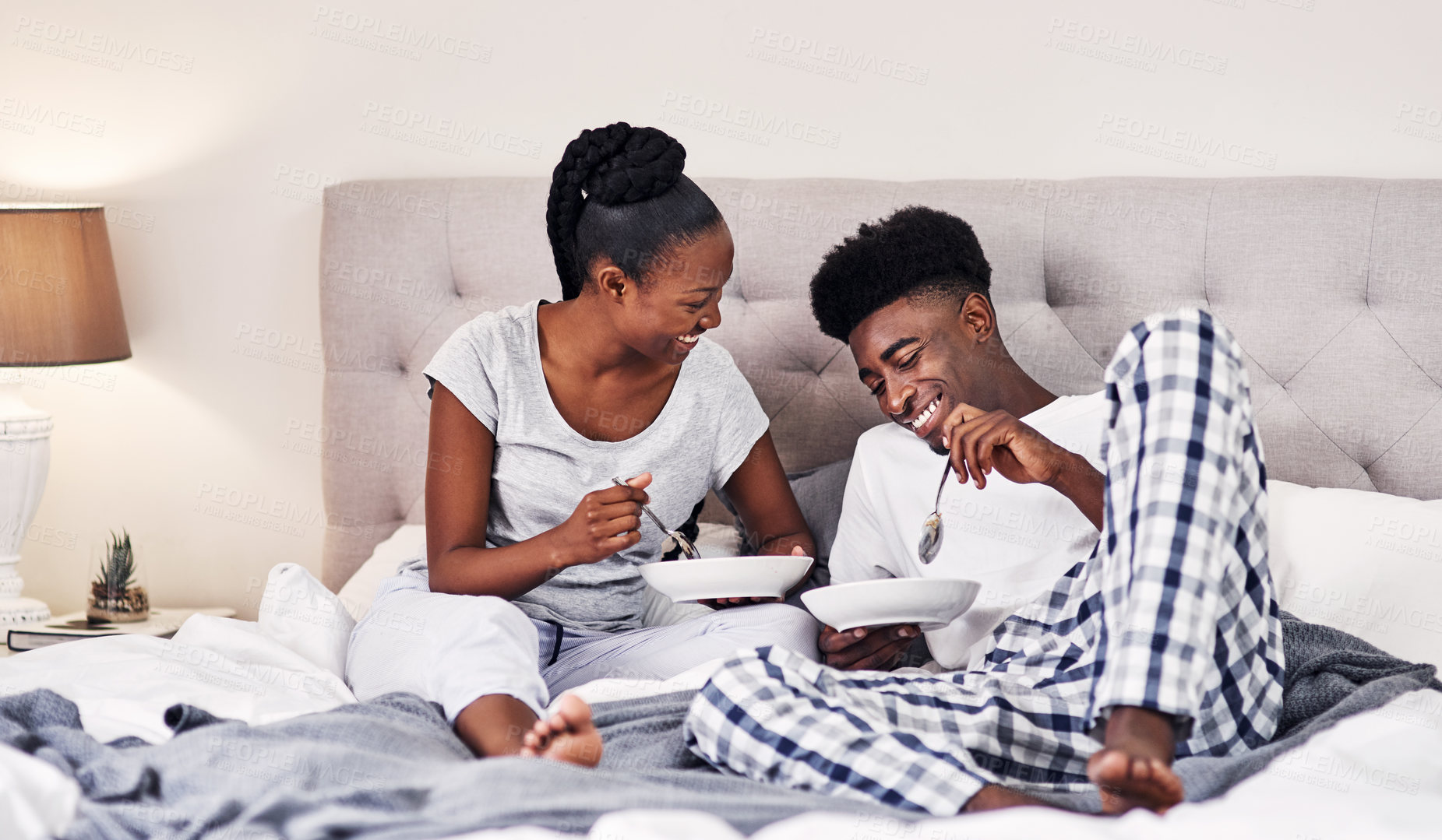 Buy stock photo Shot of a happy young couple enjoying breakfast in bed together