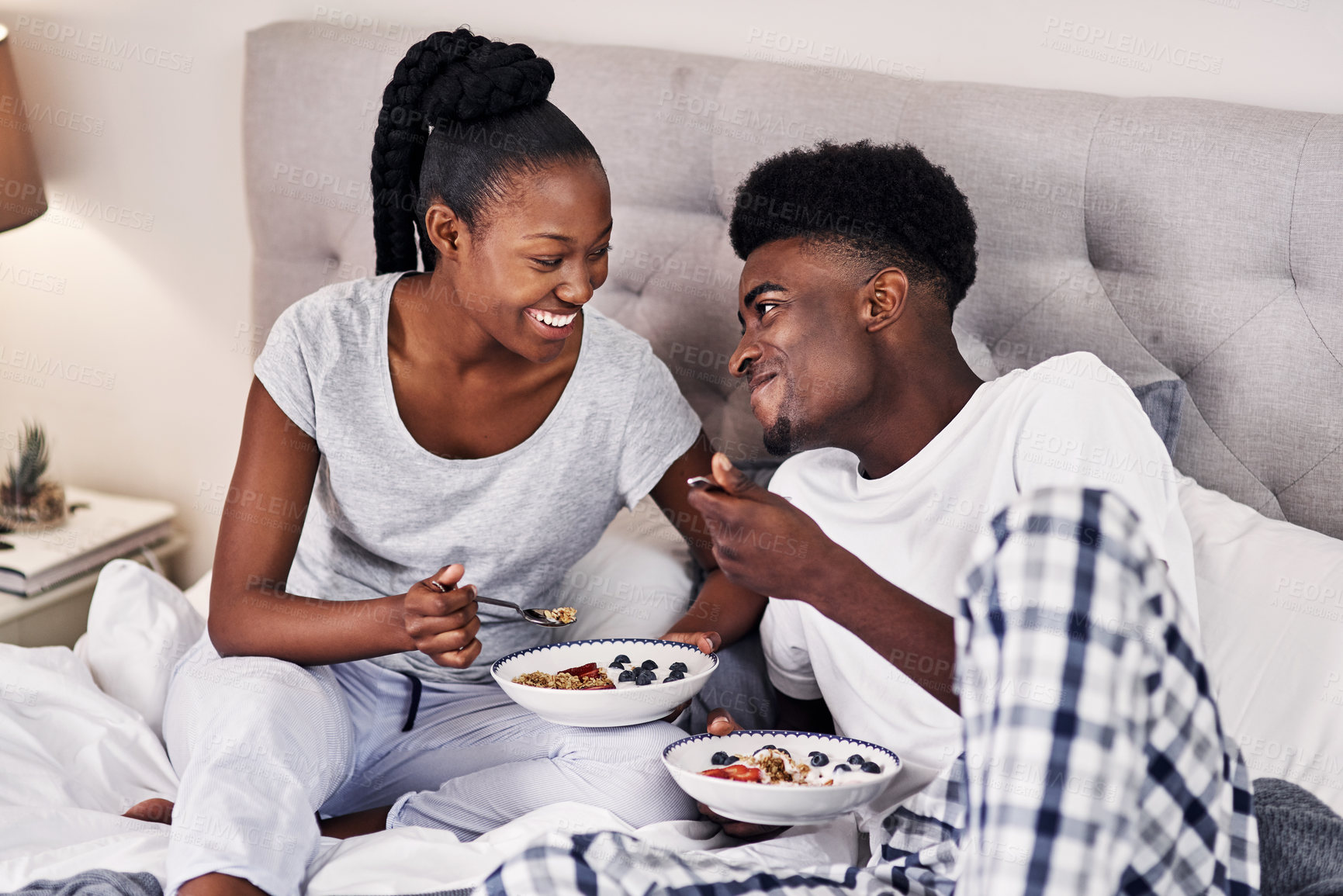 Buy stock photo Eating, love and black couple with breakfast in bed at hotel for romantic anniversary getaway. Happy, honeymoon and African man and woman with room service for healthy morning meal at lodge together.