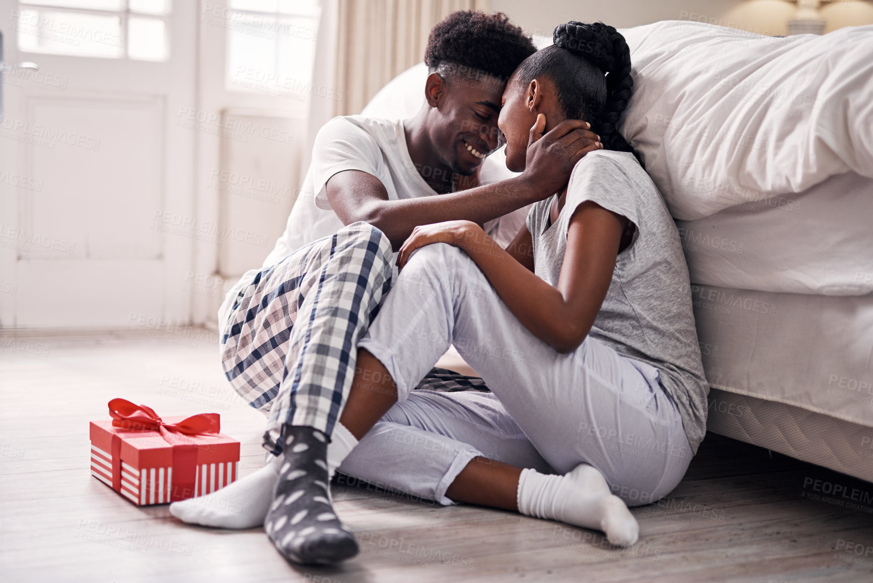 Buy stock photo Black couple, gift and happy on floor in bedroom for bonding, care and support. Relationship, love and people with present for romance, anniversary and milestone with commitment at home with smile