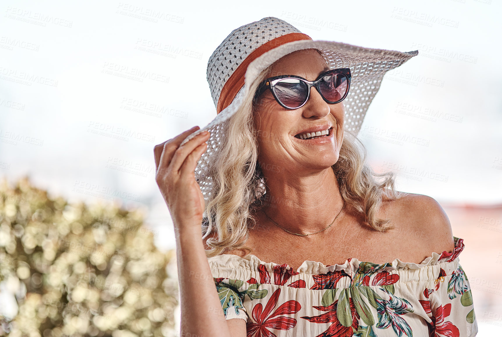 Buy stock photo Cropped shot of an attractive senior woman smiling while standing outdoors on a summer's day