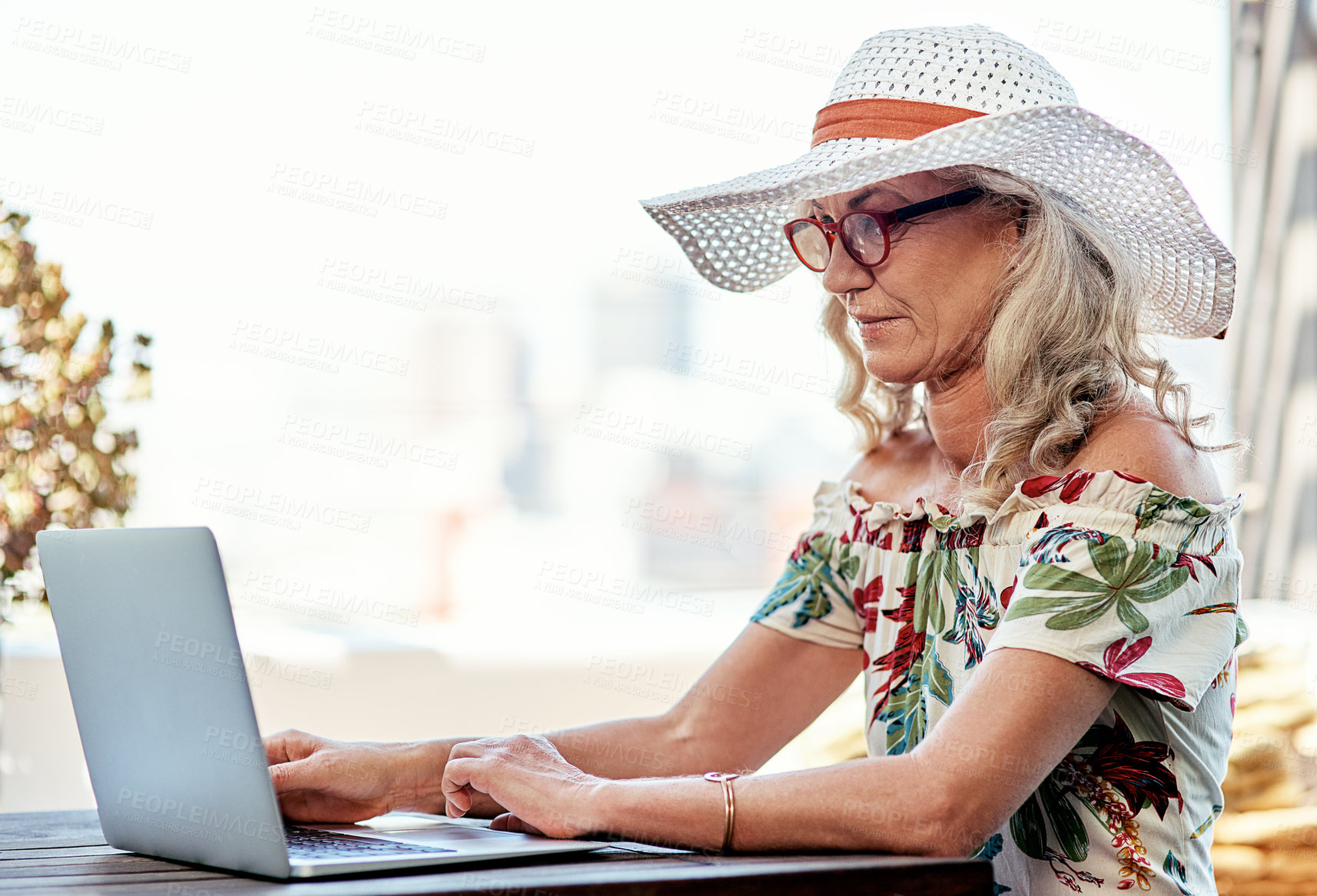 Buy stock photo Cropped shot of an attractive senior woman using a laptop while sitting outside at home