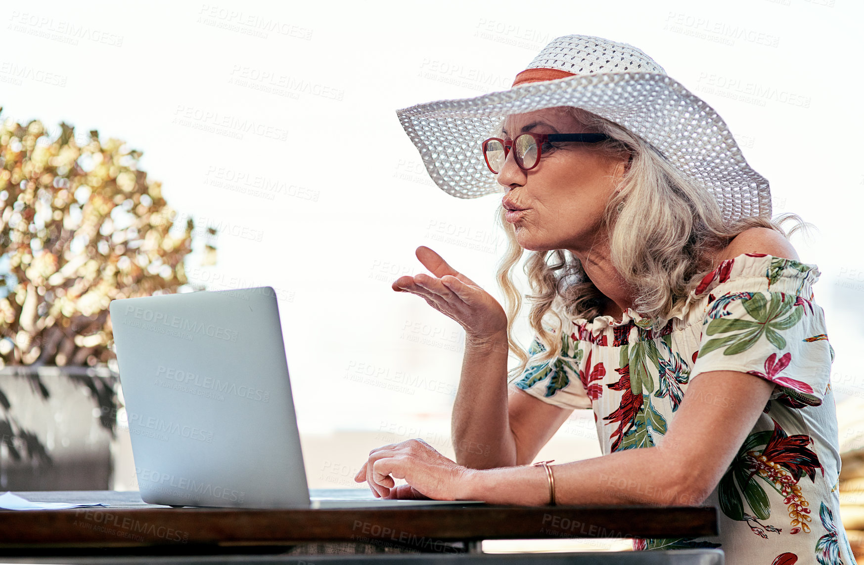 Buy stock photo Cropped shot of an attractive senior woman blowing a kiss during a video call at home