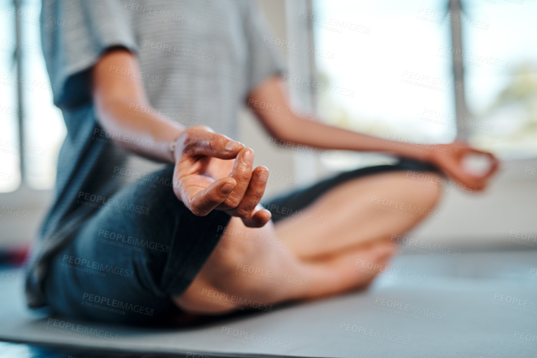 Buy stock photo Shot of an unrecognizable woman practicing yoga while meditating inside of a studio during the day