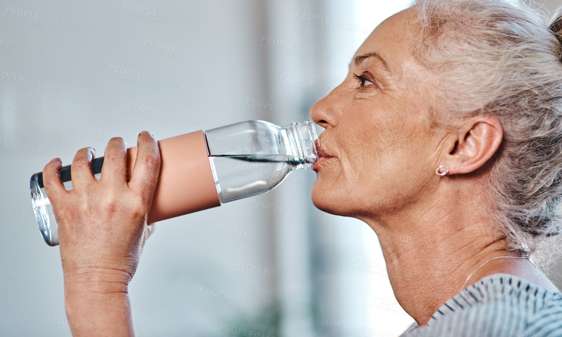 Buy stock photo Closeup of a mature woman having a drink of water inside of a studio during the day