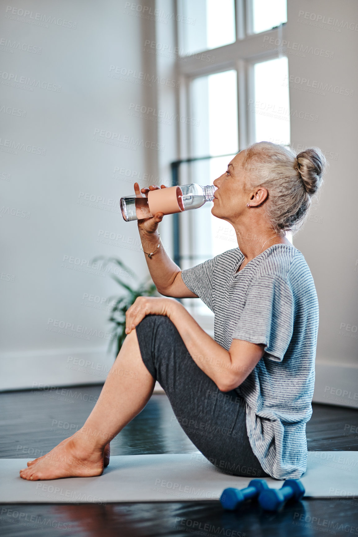 Buy stock photo Shot of a mature woman practicing yoga while having a drink of water inside of a studio during the day