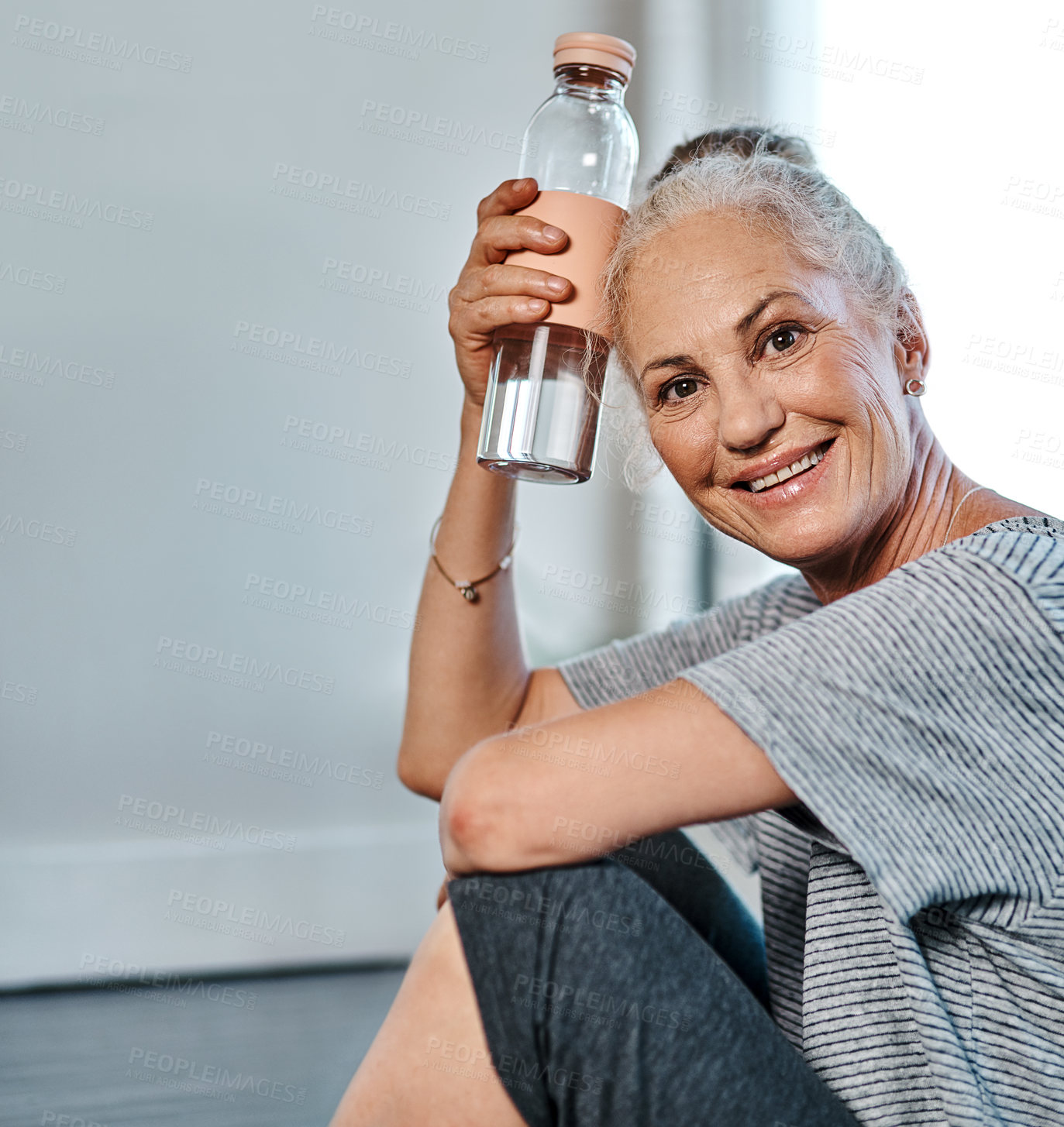 Buy stock photo Portrait of a cheerful mature woman practicing yoga while having a drink of water inside of a studio during the day
