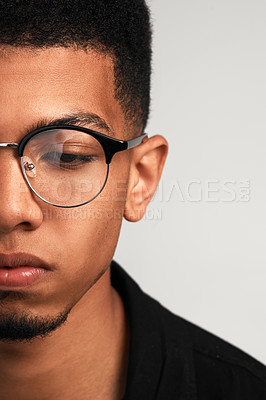 Buy stock photo Cropped studio shot of a handsome young man wearing glasses and contemplating while standing against a grey background