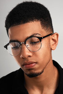 Buy stock photo Cropped studio shot of a handsome young man wearing glasses and contemplating while standing against a grey background