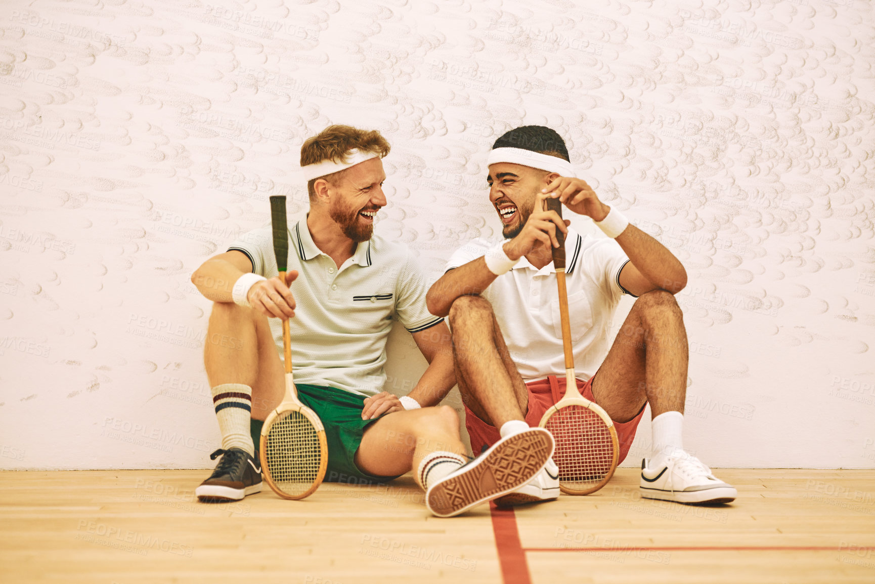 Buy stock photo Shot of two young men chatting after playing a game of squash