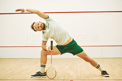 Buy stock photo Shot of a young man stretching before playing a game of squash