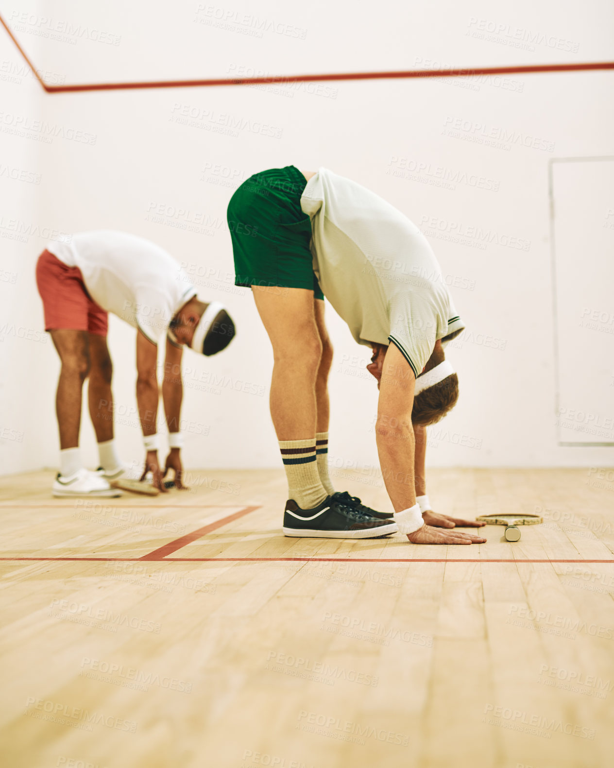 Buy stock photo Shot of two young men stretching before playing a game of squash
