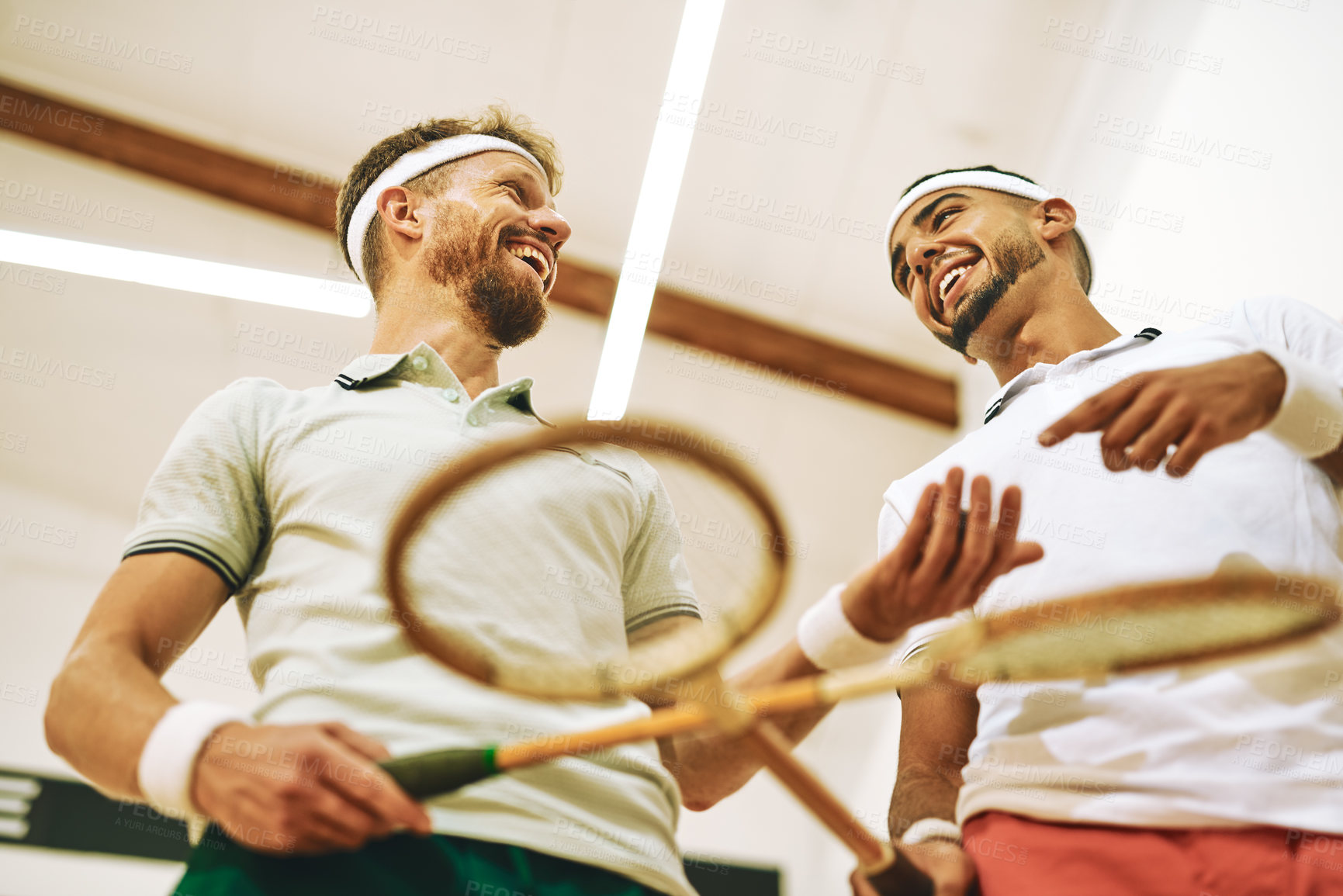 Buy stock photo Shot of two young men crossing their racquets at a squash court