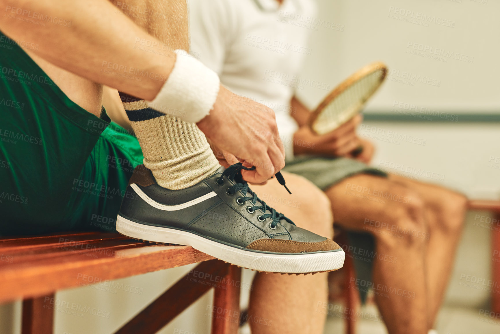 Buy stock photo Cropped shot of a man putting on his trainers in the locker room before a game of squash