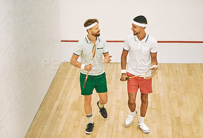 Buy stock photo Shot of two young men chatting while playing a game of squash at an indoor court