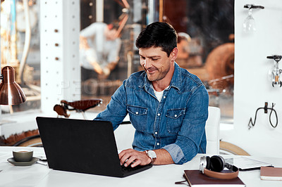 Buy stock photo Cropped shot of a handsome young businessman working on a laptop in an office inside his workshop