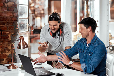 Buy stock photo Cropped shot of two young businessmen working together on a laptop in an office inside their workshop