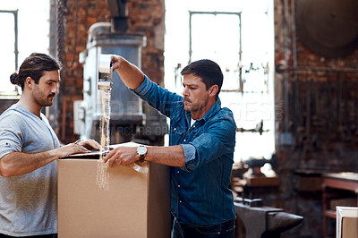 Buy stock photo Cropped shot of two young businessmen wrapping a cardboard box together while sorting out orders and deliveries inside their workshop