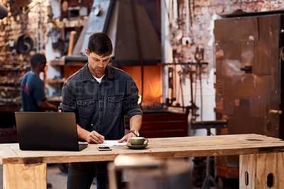 Buy stock photo Cropped shot of a handsome young businessman working on a laptop inside his workshop