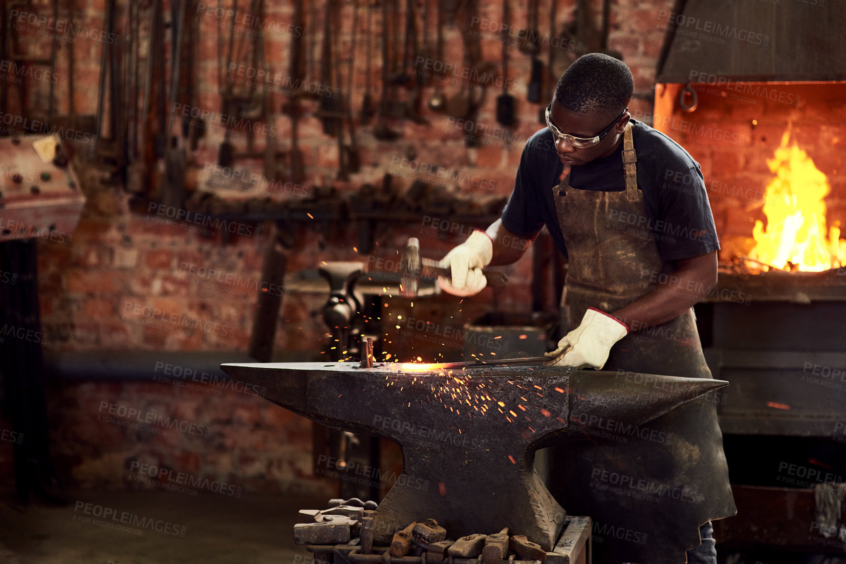 Buy stock photo Blacksmith, worker and metal forge in workshop and manual industry working on hot steel with hammer, sparks or fire. Black man, welding or iron tools manufacturing or expert, trade and dark workspace