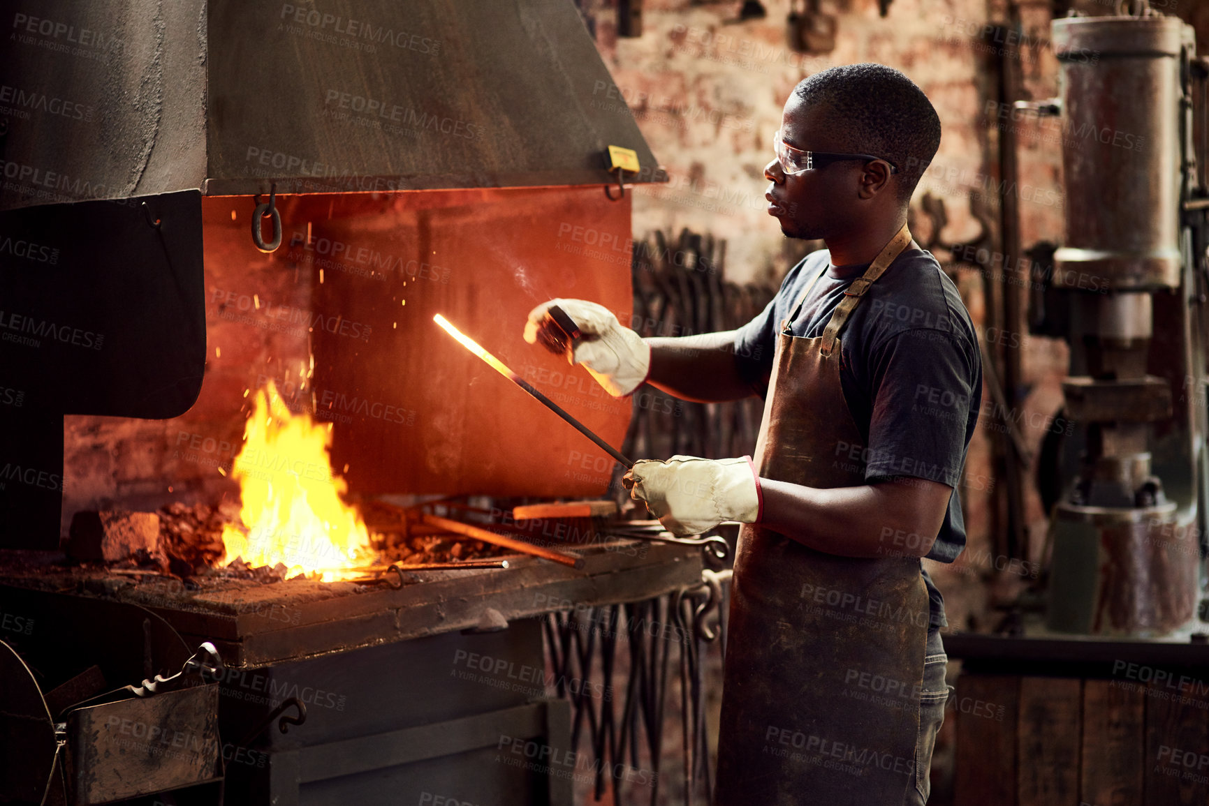 Buy stock photo Blacksmith, fire and a black man melting metal in a workshop for manufacturing or industrial design. Factory, welding or industry with a male designer in metalwork using a hot flame to melt material