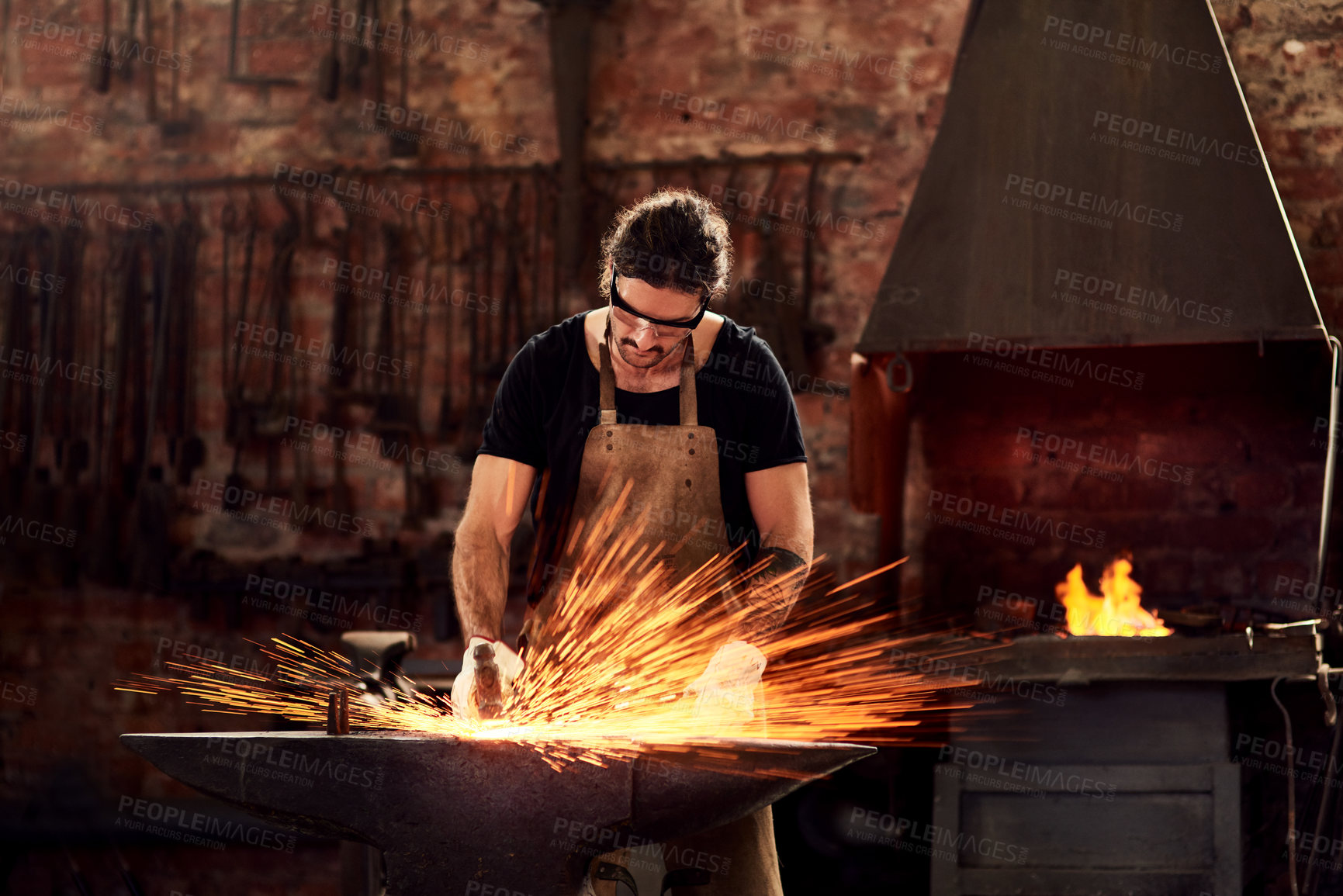 Buy stock photo Blacksmith, man and metal workshop and sparks, manual forge working on hot steel with hammer, and fire. Worker, person welding or iron tools manufacturing and expert, trade and dark workspace