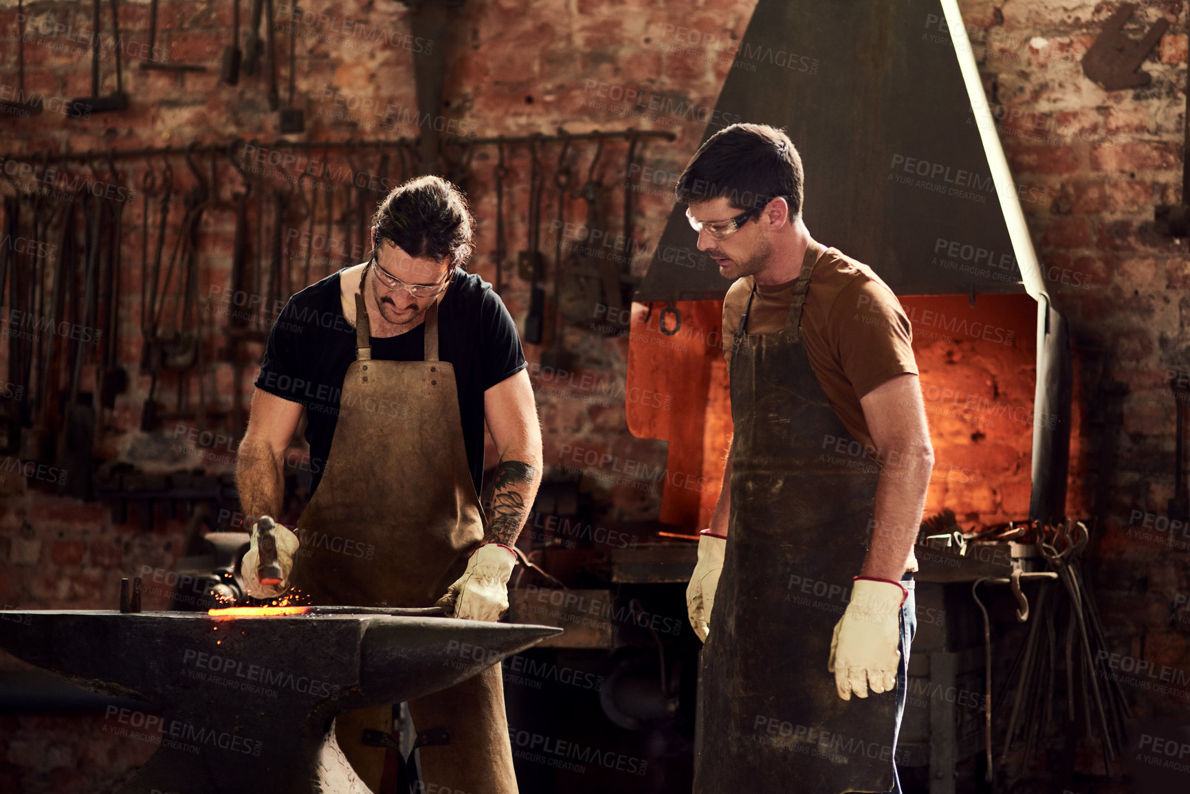 Buy stock photo Cropped shot of two handsome young metal workers working together inside a welding workshop