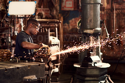 Buy stock photo Cropped shot of a handsome young metal worker using a blowtorch while working inside a welding workshop