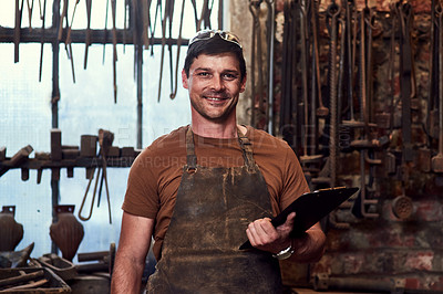 Buy stock photo Portrait of a handsome young craftsman using a digital tablet while working inside a metal workshop