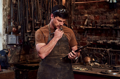 Buy stock photo Cropped shot of a handsome young craftsman using a digital tablet while working inside a metal workshop